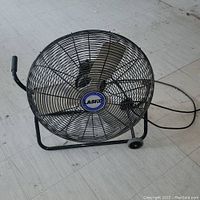 Front angle view of the Lasko industrial fan on wheels showing the protective cage, fan blades, and handle.