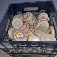 Milk crate filled with multiple rolls of new white hockey stick tape, showing many rolls packed together.