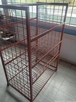 Solid red metal wire shelving unit viewed at an angle showing side, front, and top wire shelf surfaces.