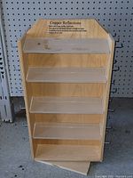 Front view of the birch plywood display shelf showing four clear acrylic shelves and angled top label panel.