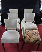 Front view of 6 dining chairs showing five beige fabric upholstery chairs and one floral fabric chair with dark wood legs.