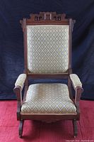 Front view of antique rocking chair showing carved wooden frame and patterned fabric upholstery