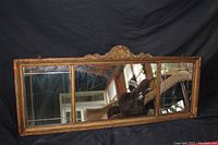 Front view of antique rectangular mirror showing carved wooden frame and floral crest detail.