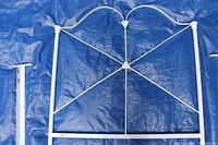 White painted antique wrought iron bed frame headboard with decorative curved and crossbar design.