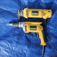 Both DeWALT drywall tools laid out on blue tarp showing both the DW 272 VSR drywall screwdriver and the DW 660 cutout tool, corded and side by side.