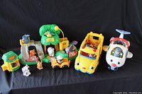 Photo showing all items including the green zoo playset, yellow school bus toy, and white airplane toy with figures.