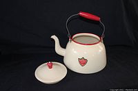 Angled side view of enamelware kettle with lid removed showing original label and red wooden handle