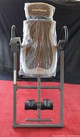 Front view of the Innova inversion table showing padded seat and adjustable headrest covered in protective plastic.