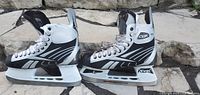 Side view of men's hockey skates showing black, white, and gray color scheme and Reebok branding.