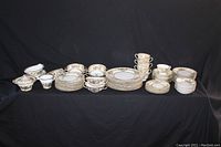 Full lot of Noritake China Iretona pattern including all plates, bowls, cups, and serving pieces arranged on black fabric background.
