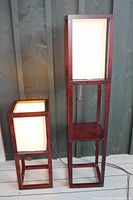Both floor lamp and table lamp shown together with lit shades, placed against wooden wall