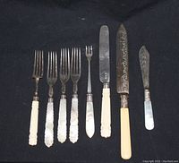 Full set of sterling silver flatware pieces including forks, knives, one carving knife with engraved blade, spreader, all with mother of pearl or ivory-like handles.