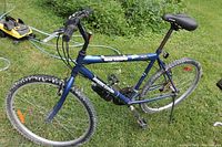 Full side view of dark blue Supercycle SC 1800 mountain bike on grass, showing frame, wheels, and handlebars.