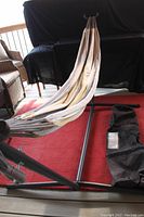Hammock set up on stand shown from side angle on red rug.