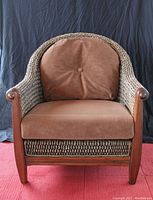 Front view of wicker chair showing brown fabric cushions and wooden arms with woven wicker back and sides.