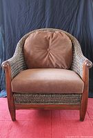 Front view of wicker chair with brown cushions and wooden arms.