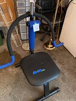 Front view of Ab-Doer Pro Model abdominal exercise machine showing padded seat, foam-covered handles, and placement in garage area.