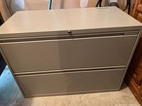Full view of the gray metal 2-drawer filing cabinet showing the lock.