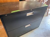 Full view of the filing cabinet showing two drawers with silver handles and scratches on front and bottom edges.
