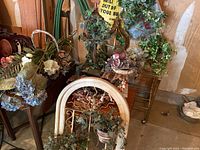 Full view of various faux greenery and floral arrangements on tables and benches with rustic decor elements