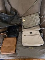 Overview of six purses of varying colors and materials arranged on couch