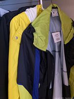 Photo showing three ladies spring jackets hanging on hooks, featuring distinct colors: yellow, black and white, and a Columbia jacket with a green collar.