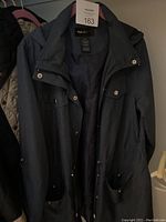 Dark colored winter coat front view showing snap buttons and pockets.