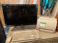 Photo of HP W2207h monitor with white wired keyboard and mouse on desk, alongside HP LaserJet 1100 printer.