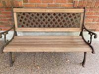 Full view of the outdoor bench showing metal lattice back and wooden seat slats with armrests and legs.
