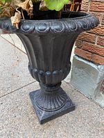 Full view of the tall black concrete urn planter showing upper rim, body, and base.