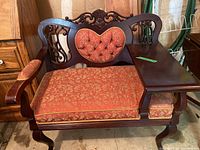 Front view of the upholstered wooden telephone chair showing floral fabric upholstery with carved backrest and attached side table.