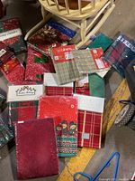 Multiple new, still sealed Christmas-themed tablecloths with varied patterns and textures visible