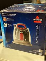 Front view of the original box showing Bissell SpotClean machine image with key features and branding.