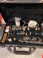 Clarinet disassembled into three main body parts with accessories placed in the black fitted case.
