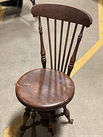 Front and partial top view of the vintage wooden swivel chair showing the round seat and spindle backrest.