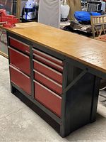 Front three-quarter view of workbench showing steel frame, wooden top, two drawer banks