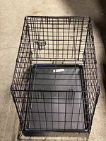Top-down view of the black metal wire dog crate with attached door and removable plastic tray.