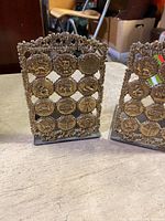 Photo of two vintage Israeli metal book ends with multiple round coin-like medallions and detailed edges.
