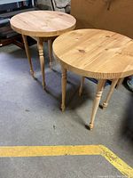 Pair of round pine side tables with turned legs, hand built, showing natural wood grain and knots on the top surfaces.