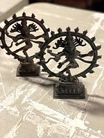 Two brass Shiva Nataraja statues side by side on tabletop