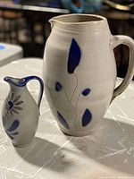 Both pottery jugs side by side showing the blue floral designs and size difference