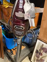 Front view of maroon Shark Rocket True Pet vacuum cleaner with tags hanging from handle and 'Superior Carpet & Bare Floor Cleaning' sticker on body.