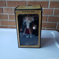 Photo of boxed Nutcracker Village Santa figurine from front, showing box with clear window