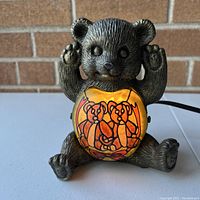 Front view of the decorative bear bedside lamp featuring an orange stained glass-style panel with bears illustration illuminated.