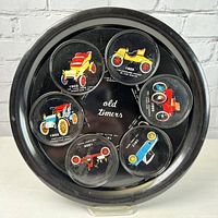 Top view of the black round metal bar tray with 6 magnetic coasters arranged inside showing colorful vintage antique car illustrations.