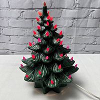 Front view of the green ceramic Christmas tree showing colorful molded bulbs in red, pink, and orange tones attached to the tree branches.