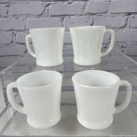 Four white opaque milk glass coffee mugs shown, two upright and two viewed from top/down.