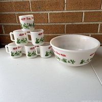 Photo showing entire set with six stacked mugs next to the punchbowl, displaying the Christmas themed prints on the milk glass.