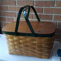 Front and top view of the vintage woven picnic basket showing hinged wooden lids, natural fiber weaving, and green wooden handles.