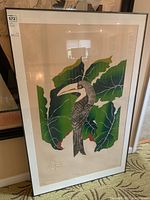 Framed print of patterned toucan with green leaves, visible embossed lizard, housed in metal frame